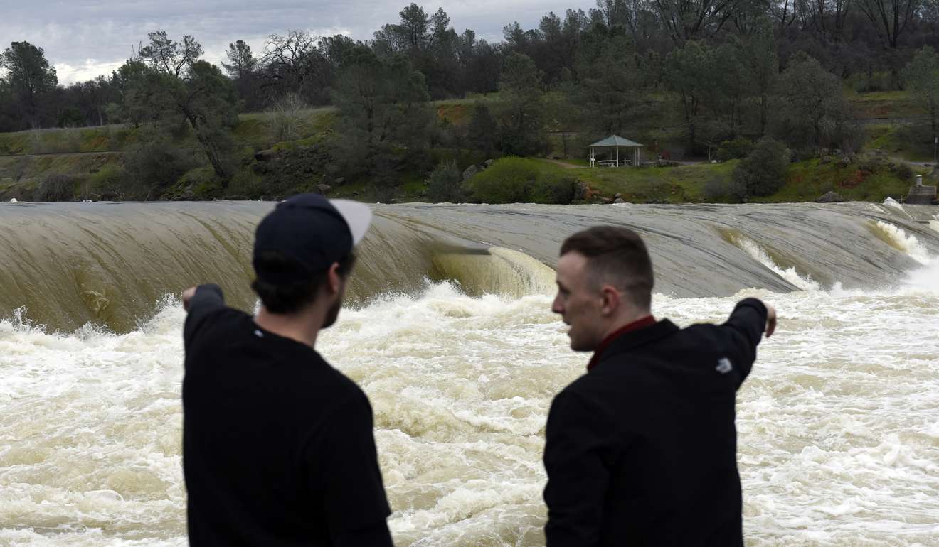 Residents watch as water from the Feather River rushes over a berm at the Feather River Fish Hatchery in Oroville, California, last week. Photo: Bloomberg