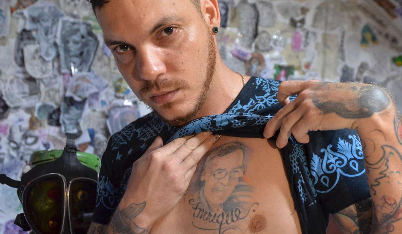 Juan Jose Herrera, 35, the son of Ismael Enrique Arciniegas, shows journalists a tattoo of his father's face . Photo: AFP