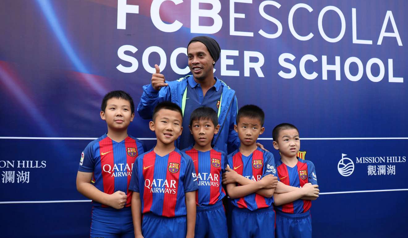 Brazilian football player Ronaldinho poses with children at the launch of a football academy on the southern Chinese island of Hainan. Ronaldinho launched a Barcelona academy for about 1,000 students in China on February 24 as the world's most populous nation pursues its grand ambitions in the world's most popular sport. / AFP PHOTO
