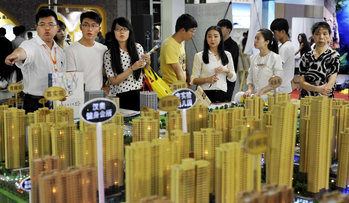 Sales representatives talk to potential buyers in front of a model of a residential complex in Wuhan in Hubei province. Photo: Reuters