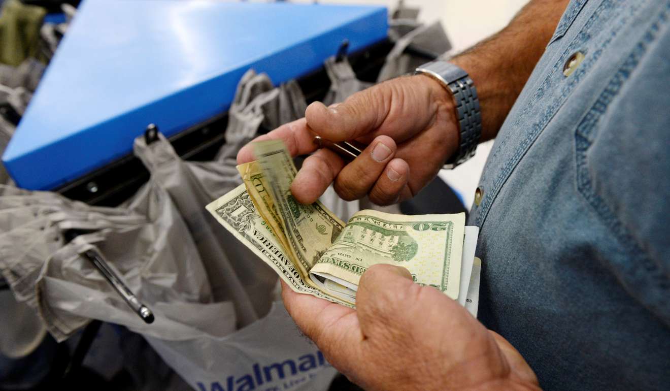 A customer counts his cash at the checkout lane of a Walmart store in Los Angeles. Photo: Reuters
