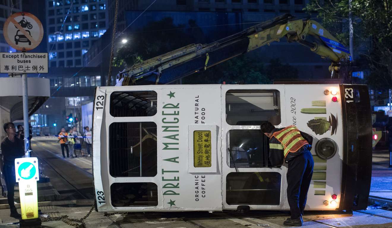 Workers inspect a tram after it fell onto its side at about midnight on Thursday. Photo: EPA