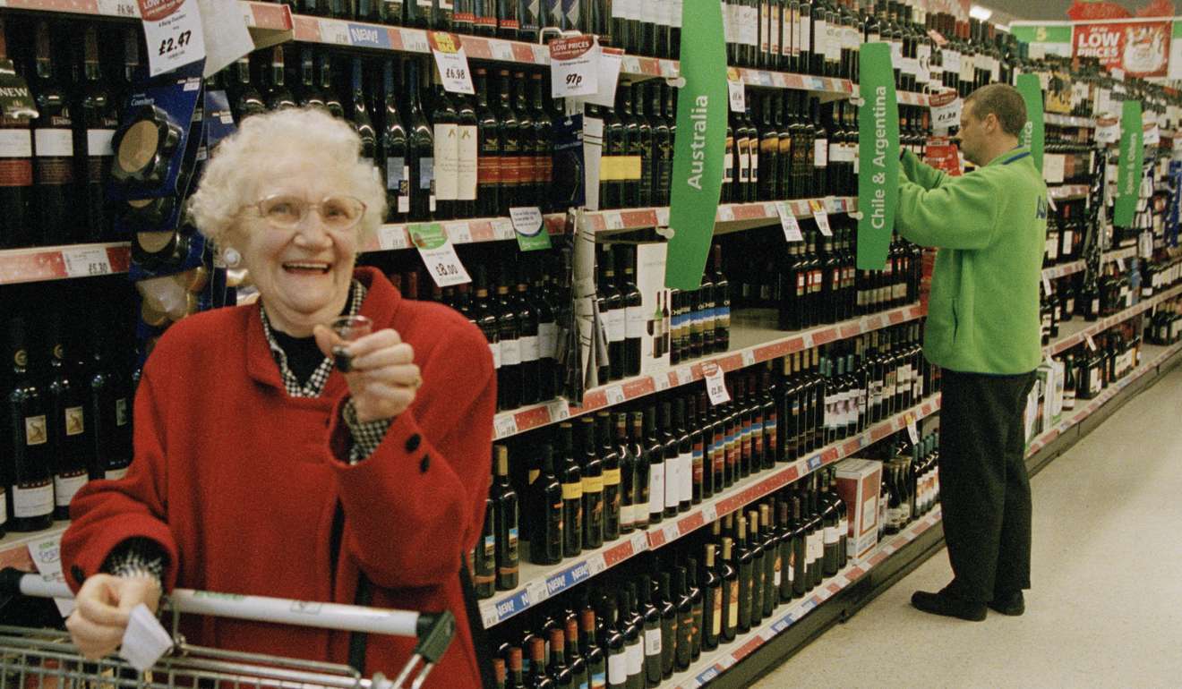 An elderly British shopper enjoys a complementary glass of red wine in an Asda store in Yorkshire, England. The UK chain was bought by Walmart in 1999. Photo: Gideon Mendel/Corbis