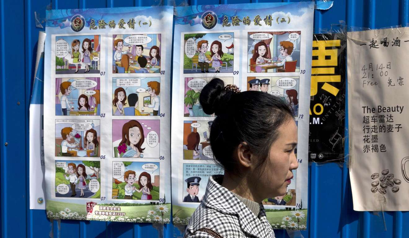 A woman walks past a poster warning against foreign spies displayed in an alleyway in Beijing. Photo: AP