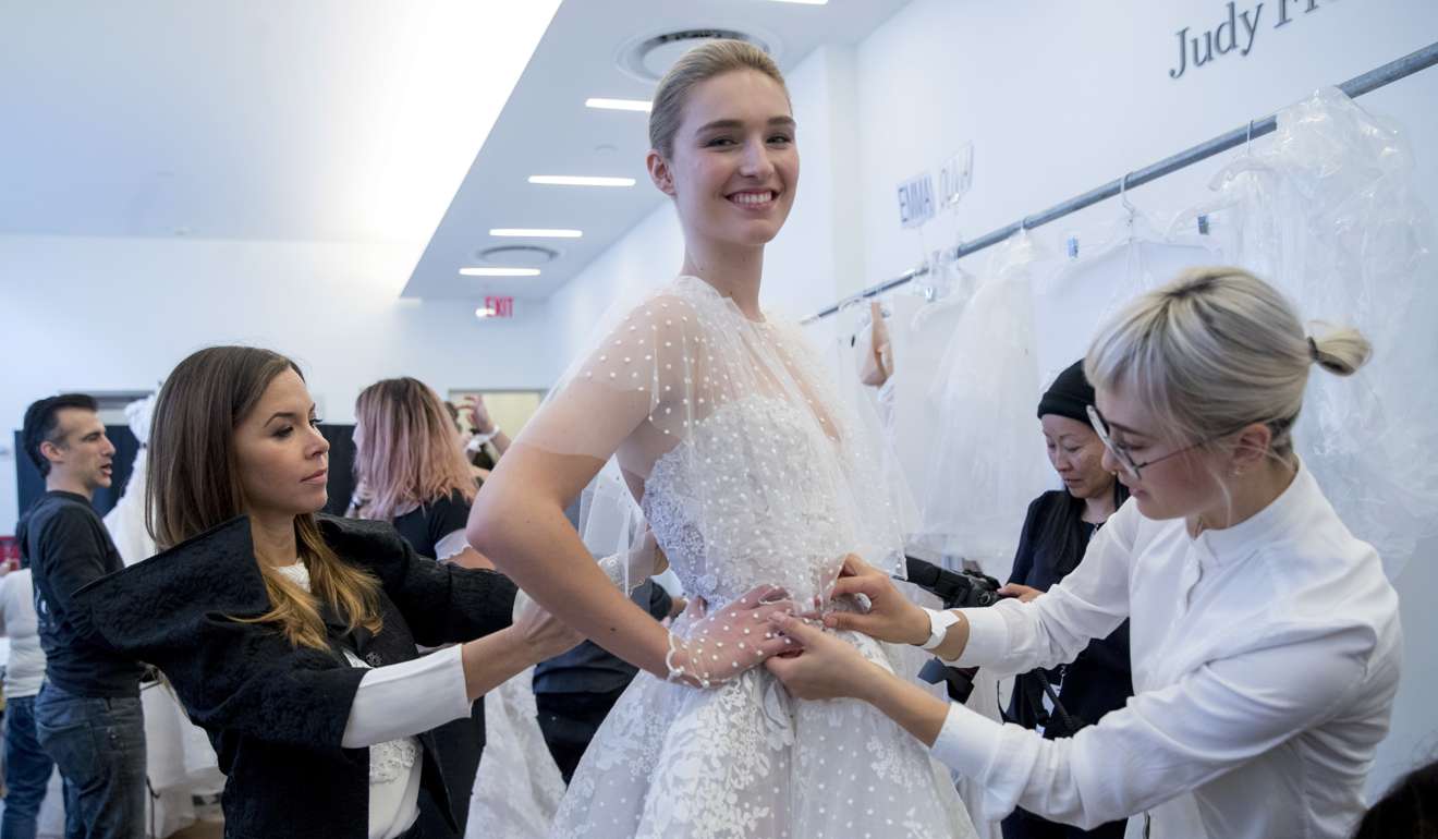 Monique Lhuillier, left, adjust a dress on a model ahead of her collection presentation during Bridal Fashion Week in New York. Photo: AP