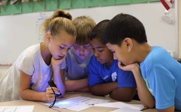 Children trying to figure out the way to get into a Breakout EDU box.