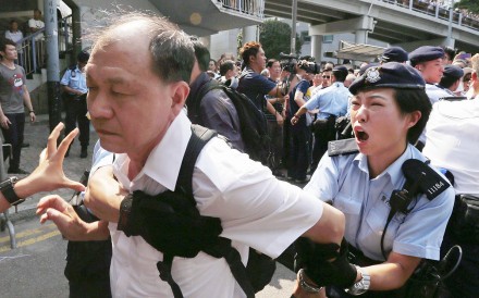 A policewoman tries to stop an anti-Occupy protester from breaking a police cordon to charge at pro-democracy protesters during a confrontation in Hong Kong on October 13, 2014. Photo: Reuters A policewoman tries to stop an anti-Occupy protester from breaking a police cordon to charge at pro-democracy protesters during a confrontation in Hong Kong on October 13, 2014. Photo: Reuters