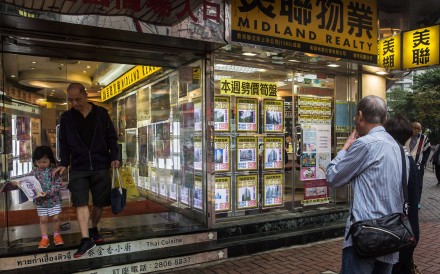 People look at residential property advertisements displayed in the window of a real estate office in the North Point district of Hong Kong. Photo: Bloomberg, Billy H.C. Kwok