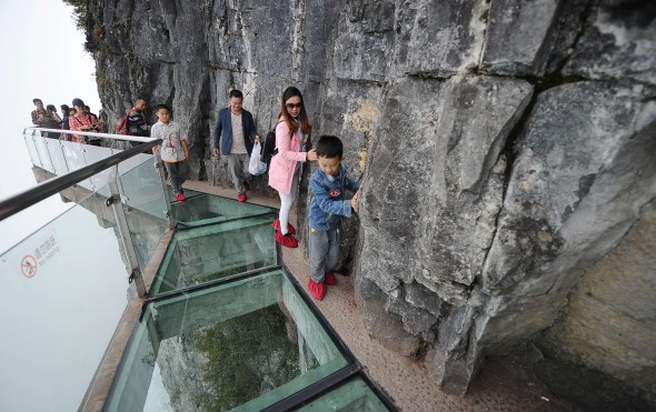 A boy and his mother try themselves best not to walk on the glass surface of a bridge while visiting a scenic spot at Tianmenshan, Zhangjiajie city in Hunan. Photo: Imaginechina