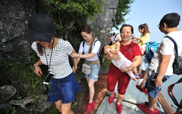 Tourists walk on the 100-meter-long and 1.6-meter-wide glass skywalk on the cliff of Tianmen Mountain in Zhangjiajie National Forest Park in Zhangjiajie city, central China's Hunan province. Photo: Imaginechina