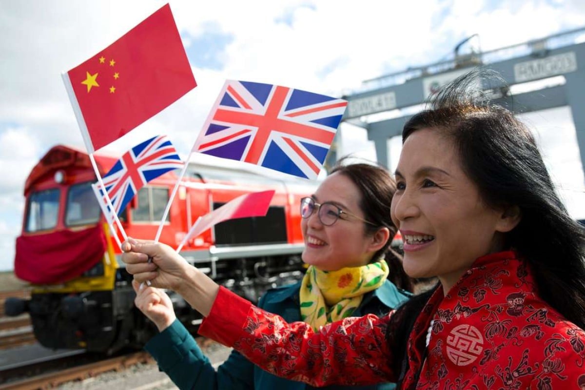 Ondata di persone le bandiere cinesi e dell'Unione in quanto rappresentano per fotografie durante la partenza di un treno merci contenitori adibiti al trasporto carichi di merci provenienti dal Regno Unito in rotta a Yiwu, nella provincia cinese orientale di Zhejiang.  Foto: AFP