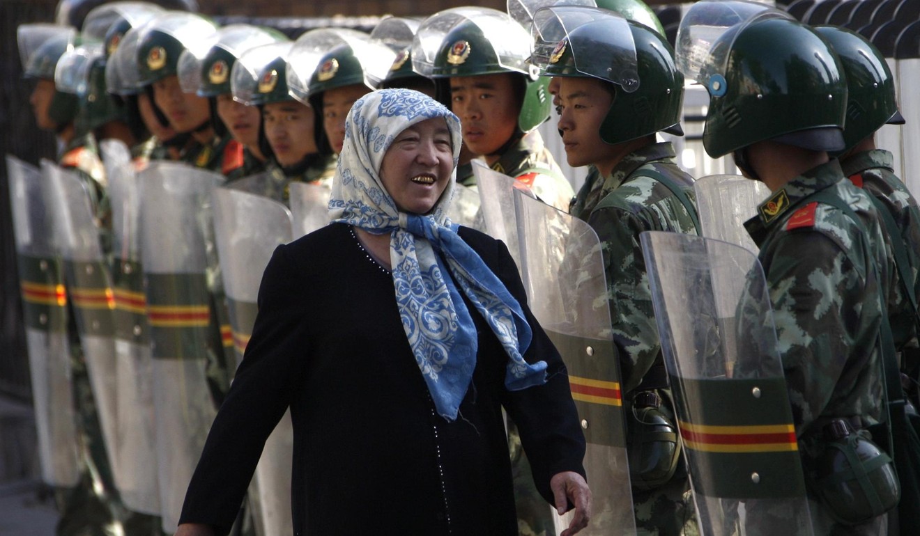 A Uygur women walks past a long line of soldiers guarding the closed Grand Bazaar in Urumqi in July 2009. Photo: EPA