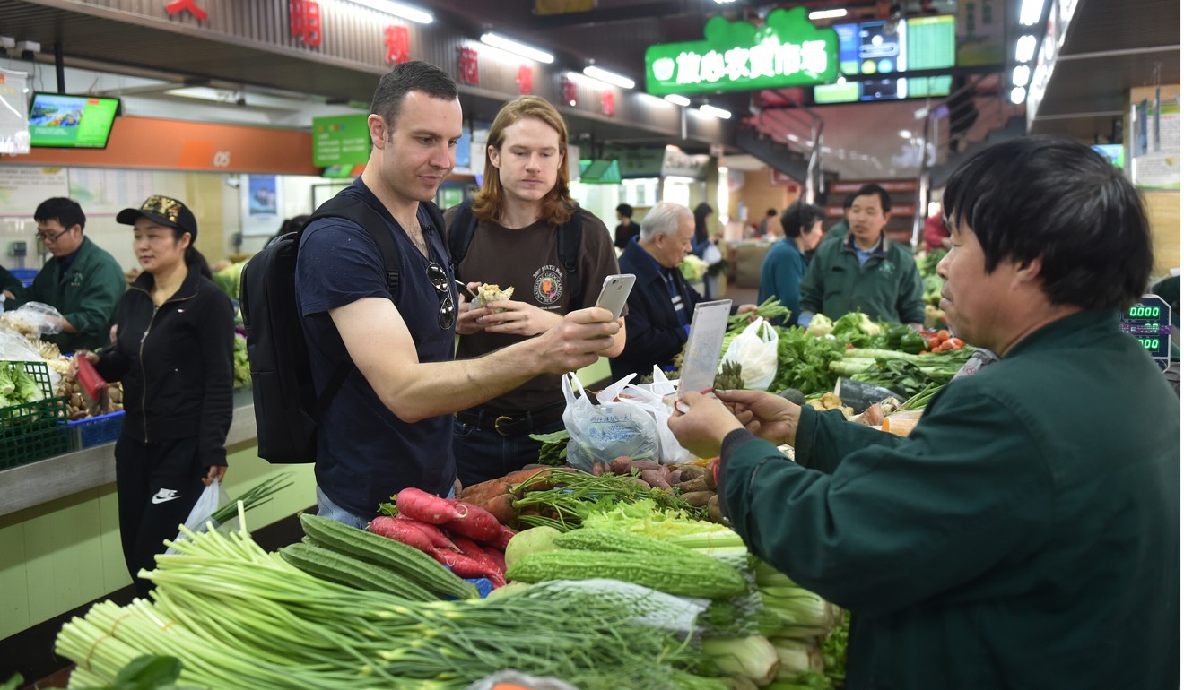 A Hangzhou resident and his friend buy vegetables through mobile payment last month at a market in Hangzhou, said to be the world's largest mobile-payment city. More than 98 per cent of Hangzhou’s taxis, over 95 per cent of its supermarkets and convenience stores, and more than 50 per cent of its restaurants have access to mobile payment services. Photo: Xinhua