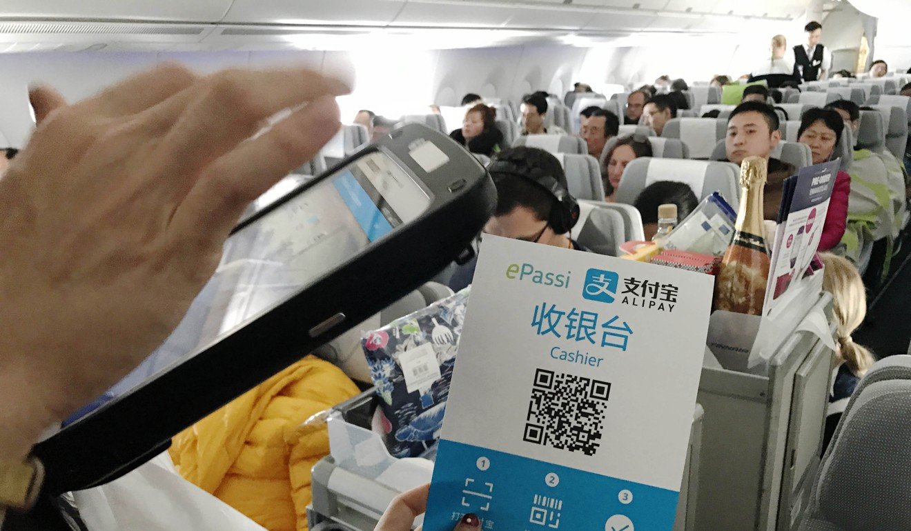 A flight attendant collects payment with Alipay on a flight bound for Helsinki from Beijing. With a smartphone, people can pay for almost everything, such as repairing cars, paying for a taxi or registering at a hospital. Photo: Xinhua