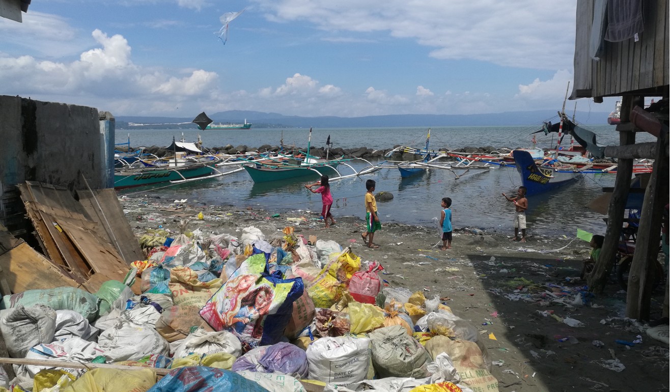 Children fly kites made from plastic bags near a pile of rubbish on Davao’s seafront. Photo: Kristin Huang