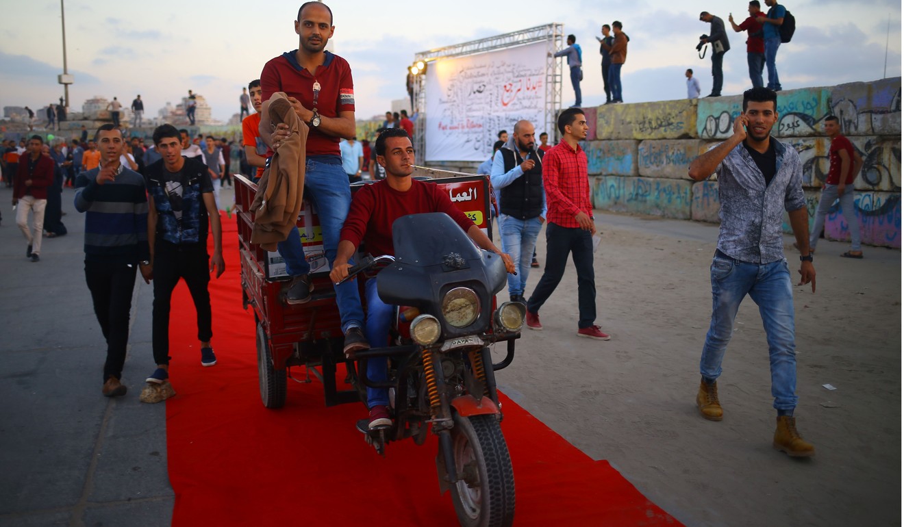 Palestinians walk on the red carpet during a festival showcasing films focusing on human rights in Gaza City on May 12, 2017. Photo: AFP