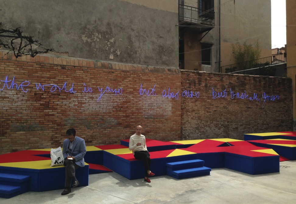 Risers (2017) is an oddly shaped platform that visitors like to sit on in the courtyard of the Hong Kong pavilion at the Venice Biennale. A quote attributed to Mao Zedong is on the wall behind it.