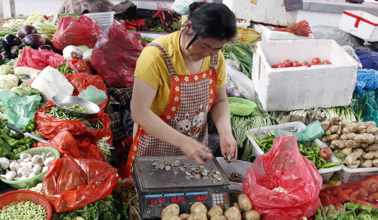 A vegetable vendor counts yuan coins while waiting at a market in Huaibei, Anhui province. The general view is growing that the Chinese government is setting its national currency on a firmer path. Photo: Reuters