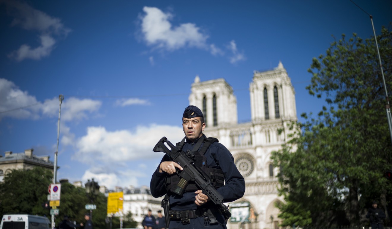 A French police officer stands guard outside of the Notre Dame cathedral after a man attacked a police officer with a hammer. Photo: EPA