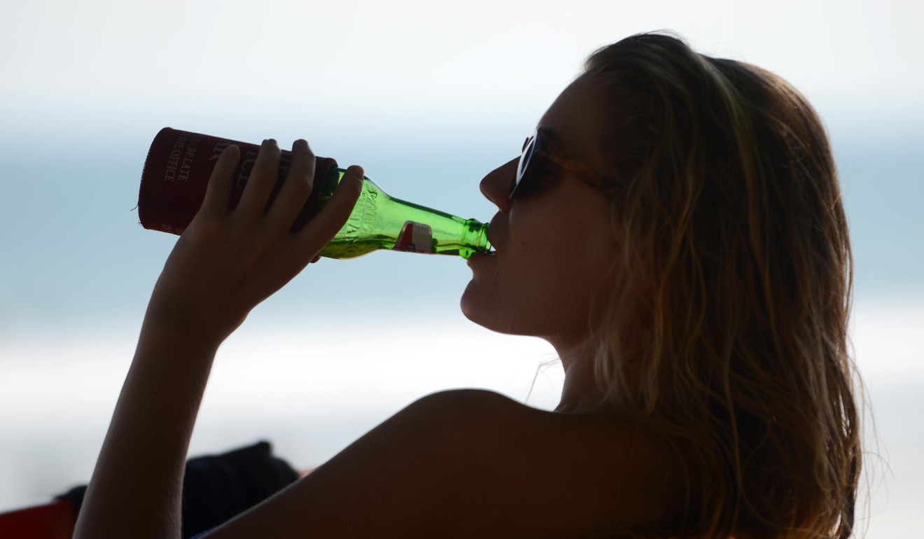 A foreign tourist drinks beer at Kuta beach, Bali. Photo: AFP