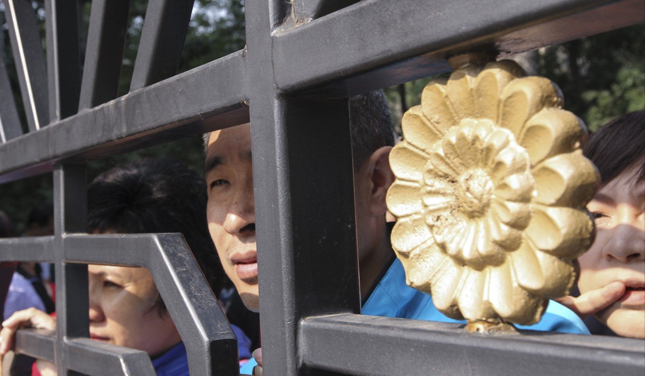 Parents look into the school through gate fence while their children taking part in the Gaokao, national college entrance exams, at Beijing No. 4 Middle School in Beijing on Jun. 07, 2017, the first day of the exams. Photo: Simon Song