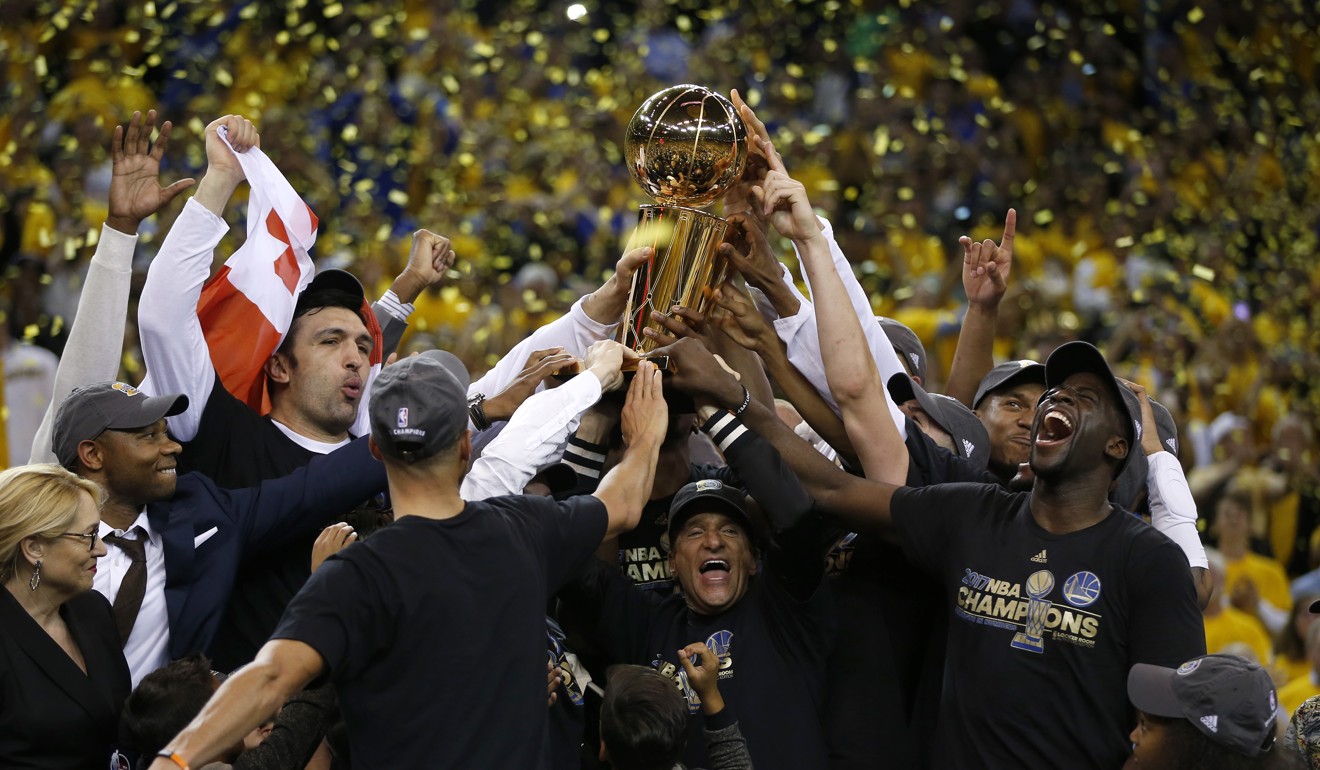The Golden State Warriors, including owner Peter Guber, hold up the NBA Finals trophY. Photo: TNS