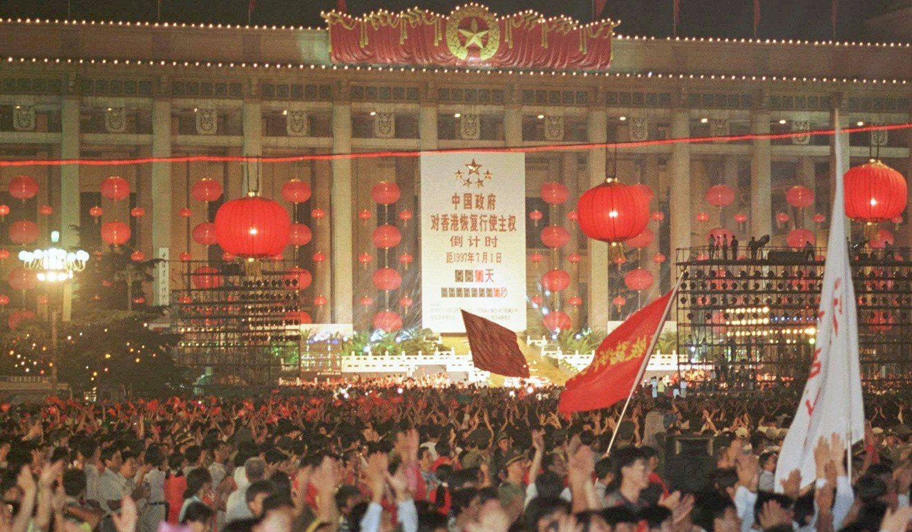 Chinese cheer and wave flags at midnight as they watch the Hong Kong countdown clock strike zero at midnight in Beijing’s Tiananmen Square on July 1, 1997. Photo: AP