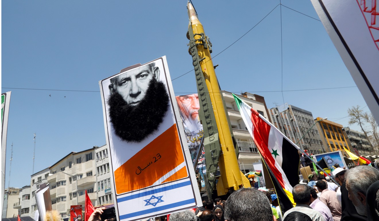 Iranians hold a cartoon of Israeli Prime Minister Benjamin Netanyahu in front of the Shahab-3 long range missile during a rally marking Quds Day. Photo: EPA