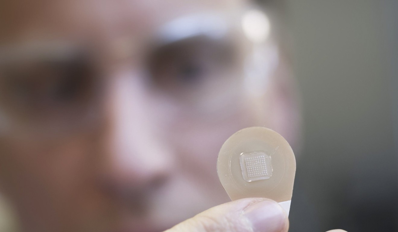 Georgia Tech’s Professor Mark Prausnitz holds up a micro-needle vaccine patch containing needles that dissolve into the skin. Photo: Christopher Moore, Georgia Tech