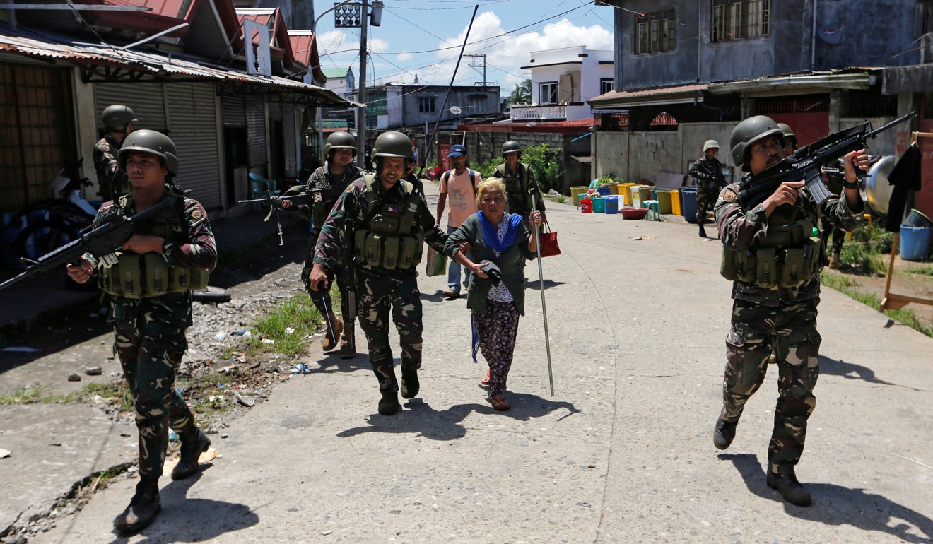 A woman is rescue by soldiers from the combat zone in Marawi. Photo: Reuters