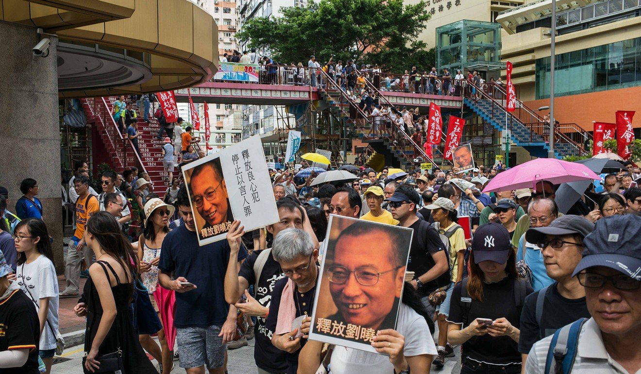 Protesters hold pictures of Liu as they march during a demonstration in Hong Kong on July 1. Photo: Bloomberg