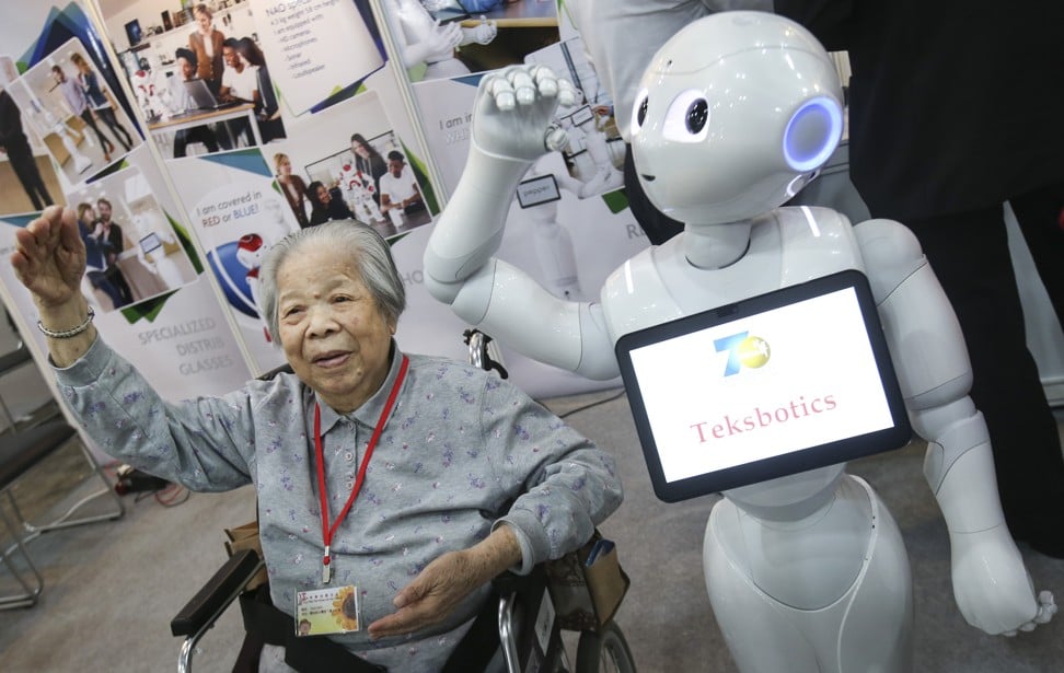 Fong Ying, 85, who visited the Gerontech & Innovation Expo with friends of her nursing home, followed dance steps of an intelligent robot, part of the exhibits on display at the Hong Kong Convention & Exhibition Centre on June 16. Photo: SCMP/David Wong