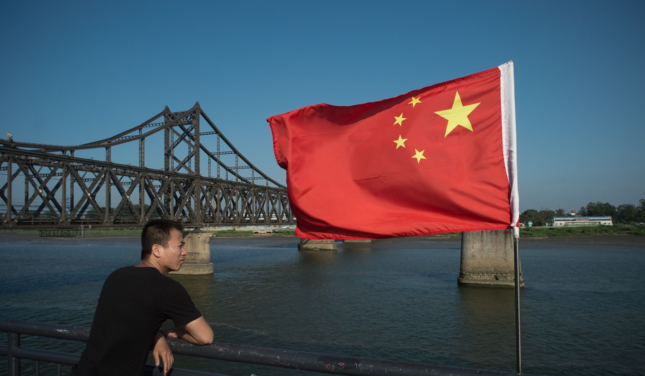 A tourist looks out from the Broken Bridge next to the Friendship Bridge on the Yalu River connecting the North Korean town of Sinuiju and the Chinese border city of Dandong. Photo: AFP