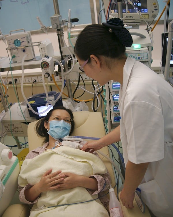 Nurse Yi Yanzhi cares for patient Ms Yu and her 56-day-old boy. Picture: Stuart Heaver