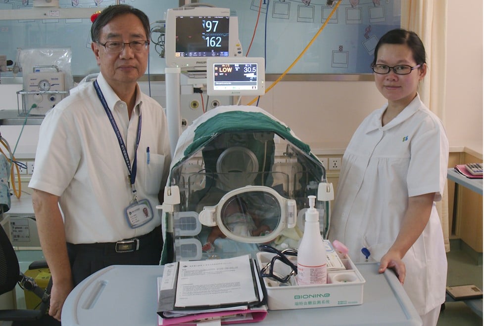 Professor Chow Chun-bong and nurse Yi watch over an infant in their care. Picture: Stuart Heaver