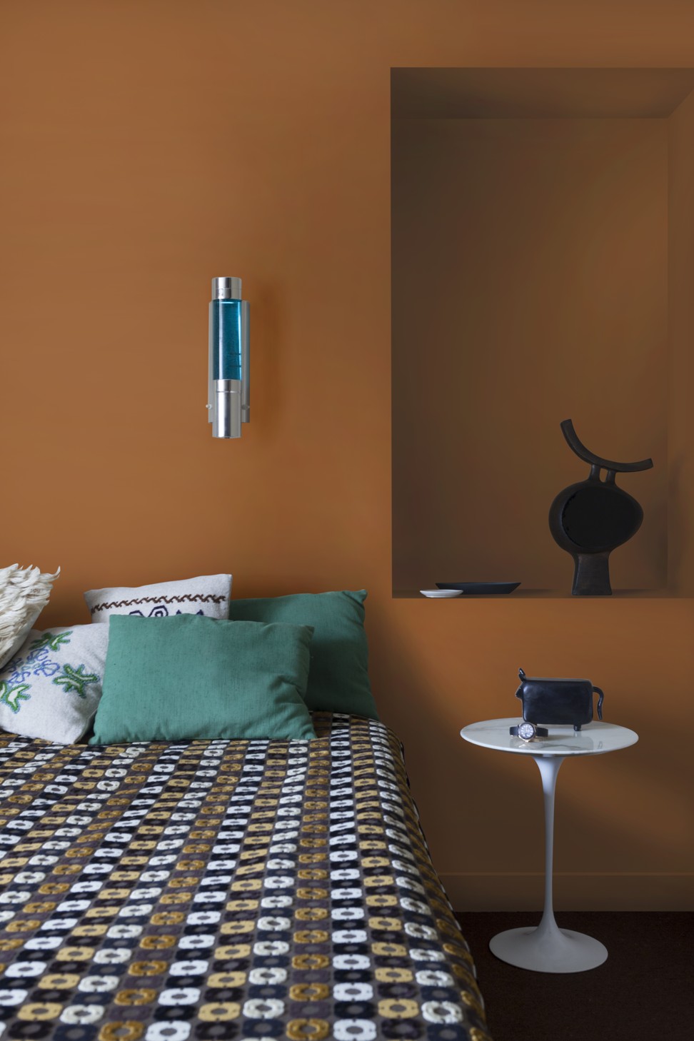 This bedroom has a strong 1970s vibe to it, with the orange and brown hues, the plastic Copenhagen lamp and the strong graphic lines on the bedspread and carpet.