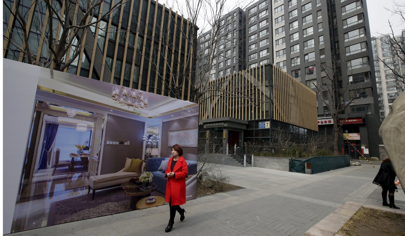 A woman walks past a property advertisement in central Beijing in March last year. Photo: Reuters