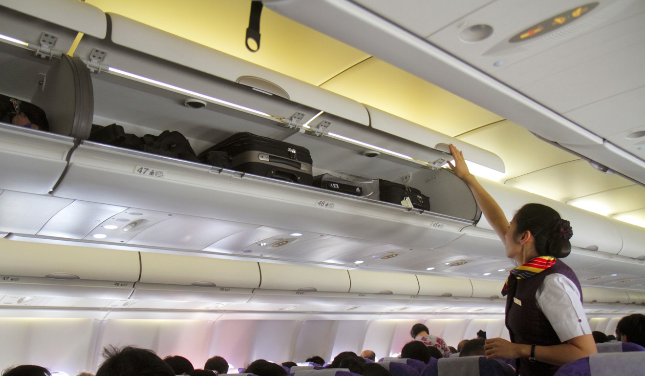 Helping passengers put hand luggage in overhead lockers is not part of the job, but something cabin crew are frequently expected to do. Photo: Alamy