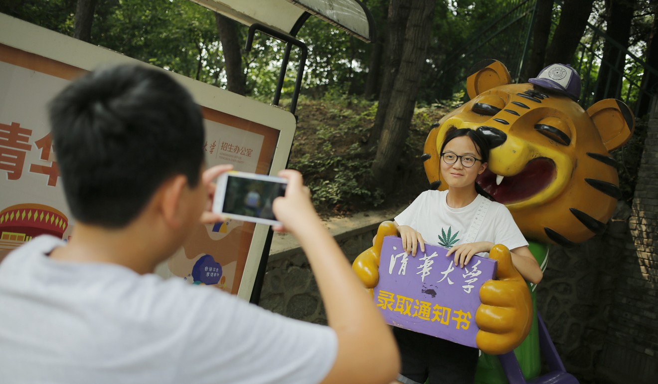 A tourist poses for a photo with a statue at Tsinghua University. Photo: EPA