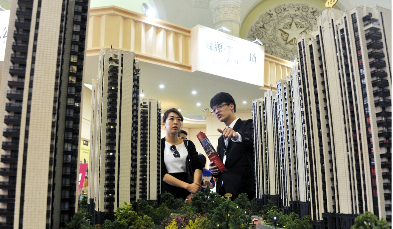A sales assistant speaks to a customer in front of a model of a residential complex, at a real estate exhibition in Shanghai. Photo: REUTERS