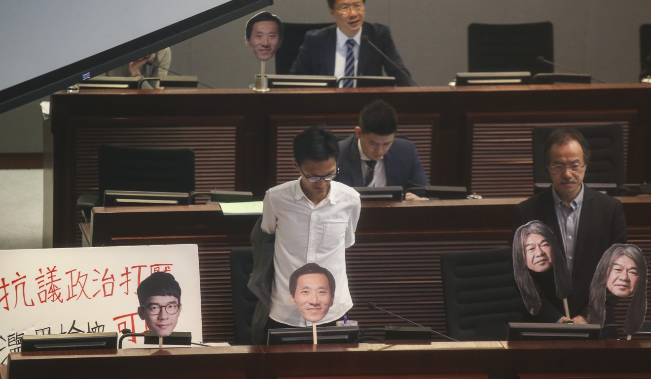 Lawmakers Eddie Chu Hoi-dick (left) and Fernando Cheung Chiu-hung with placards of disqualified fellow lawmakers attend a Legislative Council meeting Photo: David Wong