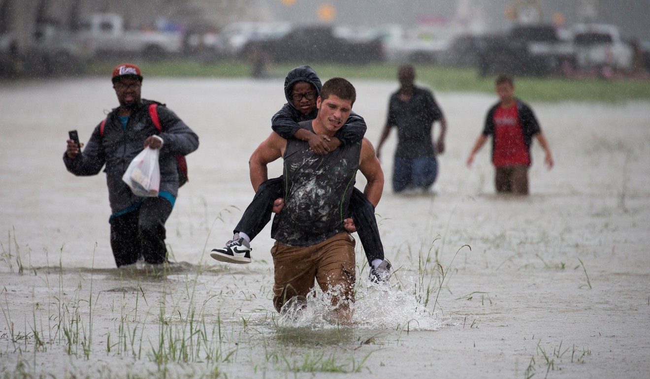 A man carries a boy to safety through floodwaters east Houston, Texas, on Monday. Photo: Reuters