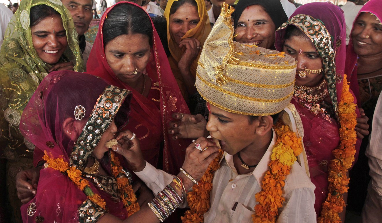A young Indian bride and her groom share sweets during a wedding organised by a local agency in the village of Vadiya, India. Photo: AP Photo