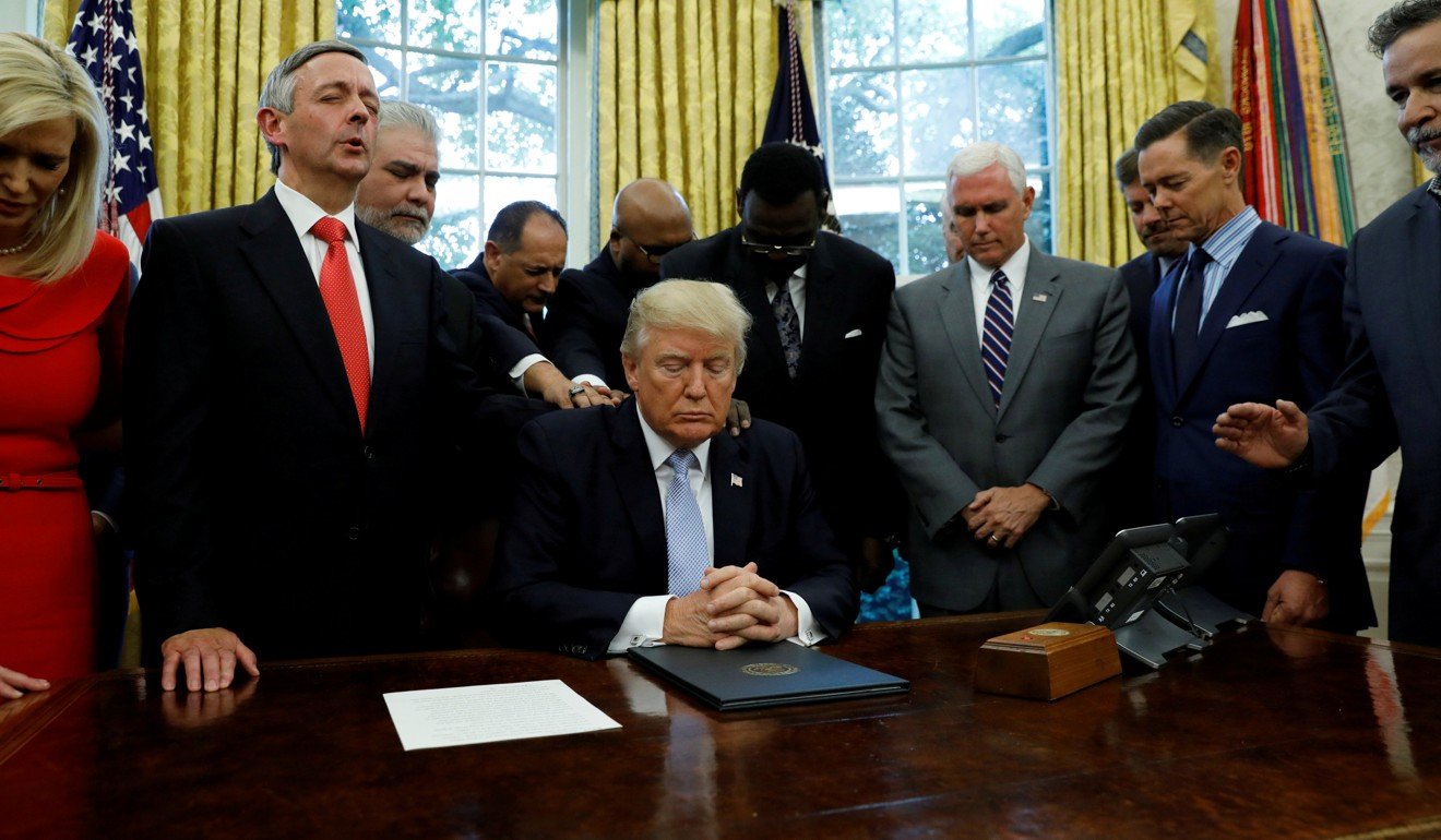 Faith leaders place their hands on the shoulders of US President Donald Trump as he takes part in a prayer for those affected by Hurricane Harvey in the Oval Office of the White House in Washington, on September 1, 2017. Photo: Reuters