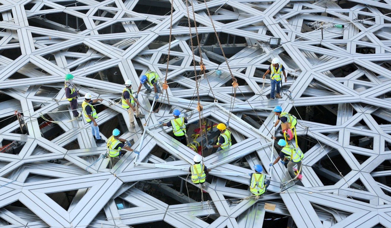 Workers place the final piece of the outer cladding of the dome structure of the Louvre Abu Dhabi museum in 2015. Photo: AFP/WAM/HO