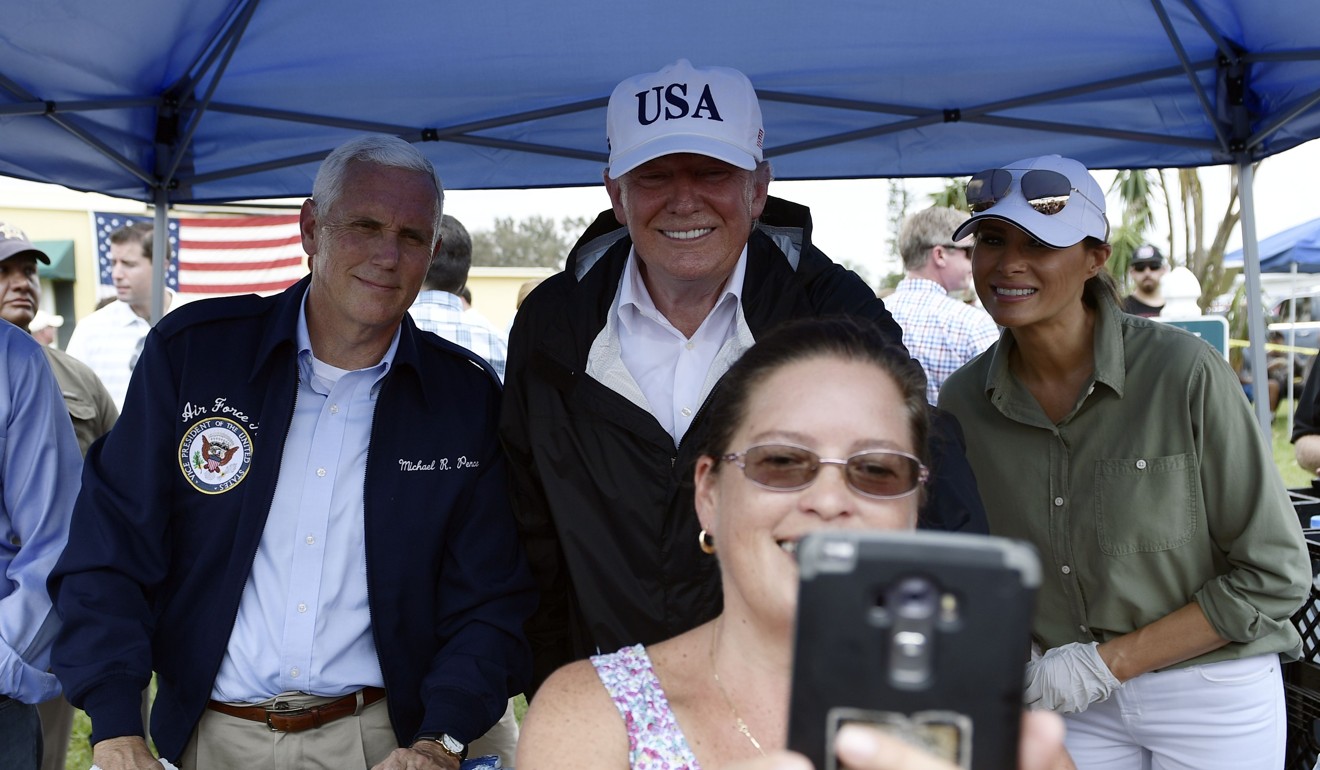 US President Donald Trump (C), US Vice President Mike Pence (L) and First Lady Melania Trump pose for a selfie as they help serve food to people affected by Hurricane Irma, in Naples, Florida, on September 14, 2017. Photo: AFP