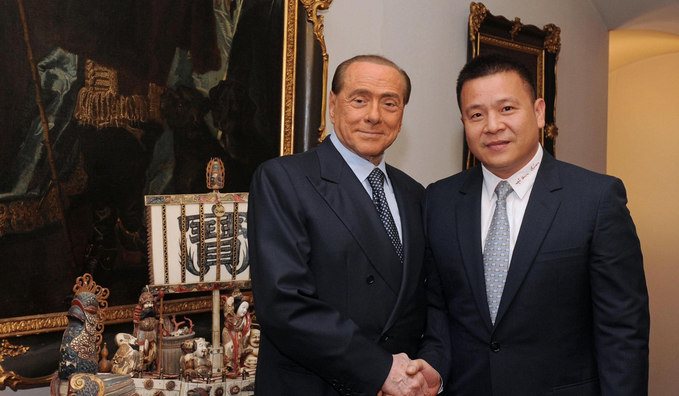The new owner of AC Milan football club Li Yonghong (R) shakes hands with former AC Milan president Silvio Berlusconi. Photo: AFP