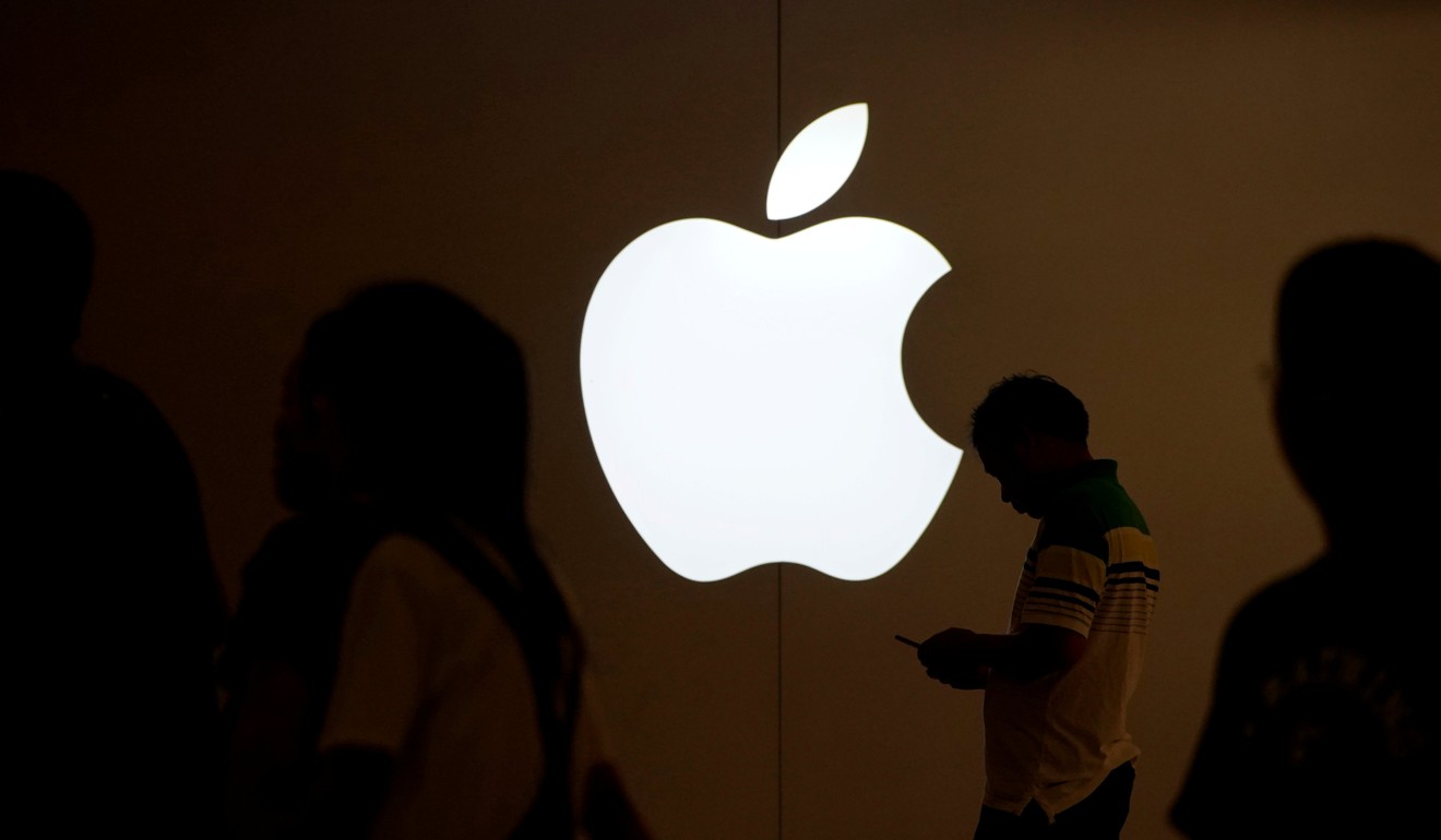 A man looks at the screen of his mobile phone in front of an Apple logo. The tech giant is one of several members of a consortium buying the chip unit of Toshiba. Photo: Reuters