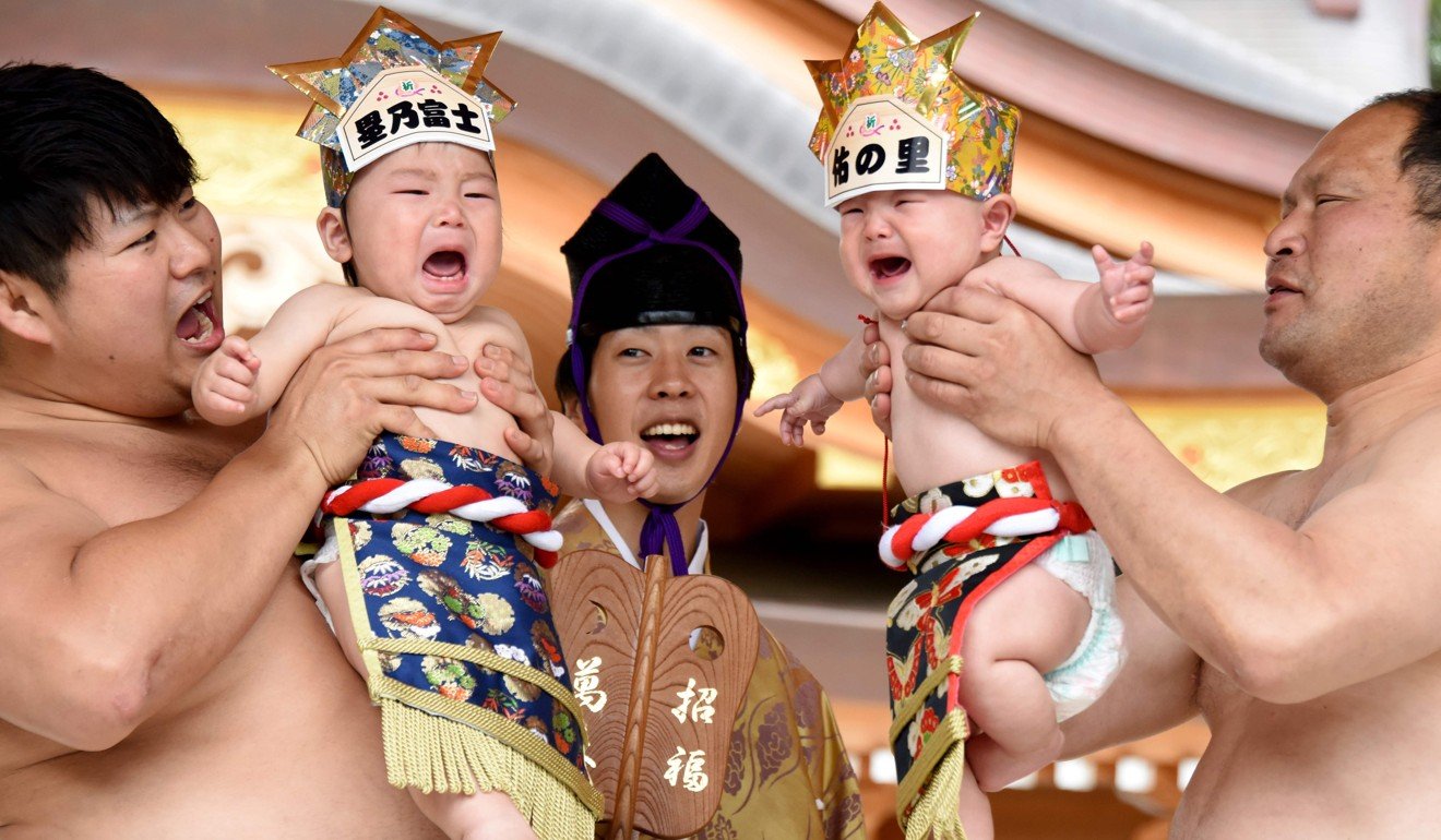 Sumo wrestlers hold up crying babies in front of a referee during a Baby-Cry Sumo event at the Kamegaike-Hachiman Shrine in Sagamihara, Kanagawa prefecture in May. Photo: AFP