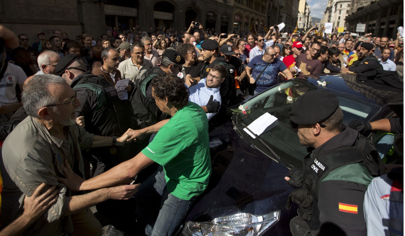 Demonstrators try to stop the car carrying Xavier Puig, a regional Catalan official, after he was arrested by Guardia Civil officers in Barcelona on Wednesday. Photo: AP